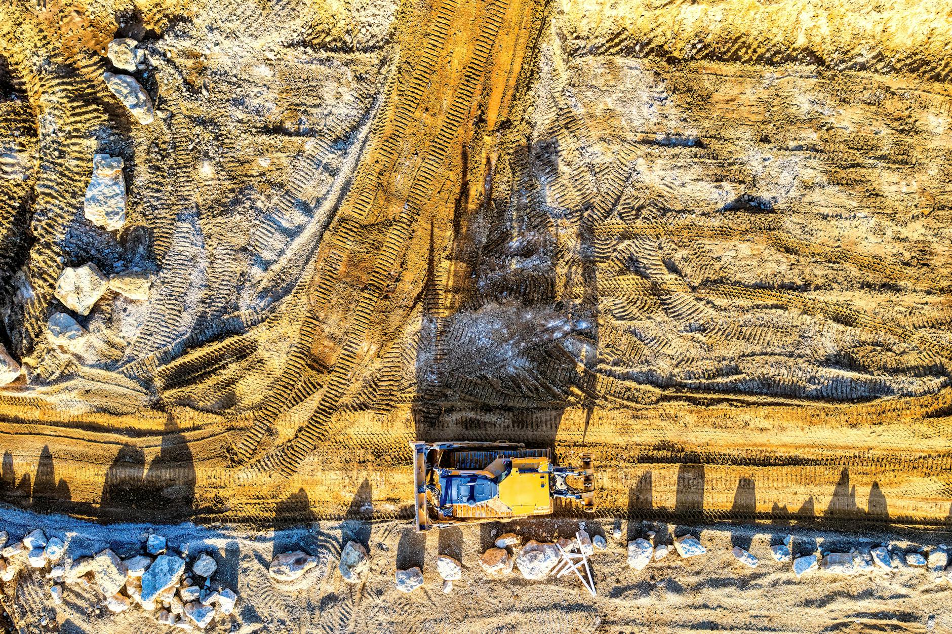 Aerial shot of construction site in Rochester, MN, featuring an excavator on dirt road.